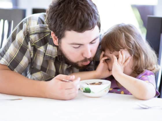 Father feeds his daughter and she doesn't want to eat. Kid refusing food. Negative reinforcement concept.