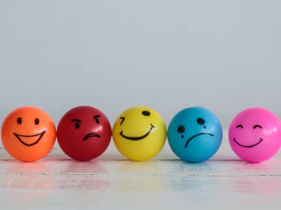 Four ping pong balls in different colors wearing different emotions.