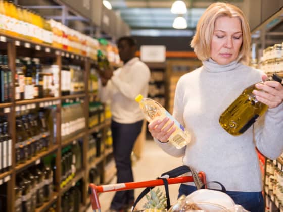 Attentive woman making purchases in store, choosing substitutes for vegetable oil